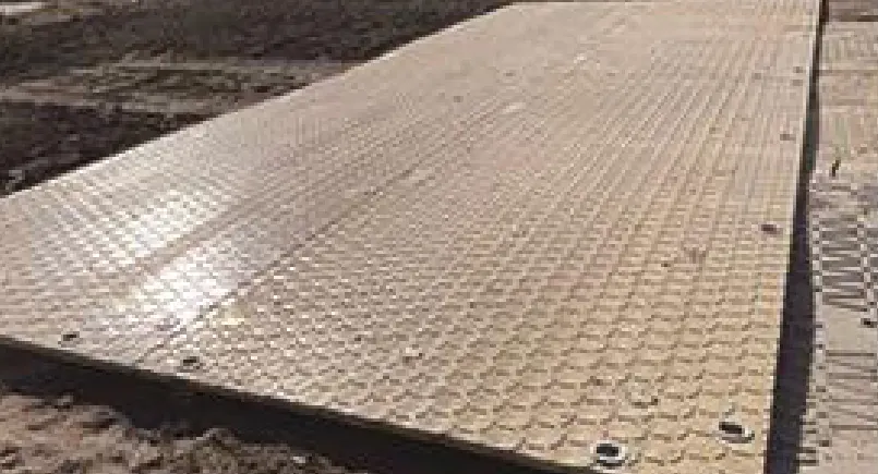 Composite access mat laid over soft ground as a temporary working platform